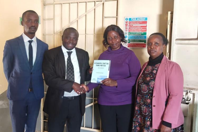 Dr. Hassan Kinyua Omari, senior Lecturer at the University of Nairobi, Director, KIFLAPS presents a copy of his book, Kiswahili Hatua kwa Hatua, to Ms. Salome Terah (Deputy Director, Directorate of Adult & Continuing Education, Ministry of Education) during a courtesy visit