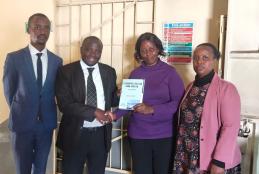Dr. Hassan Kinyua Omari, senior Lecturer at the University of Nairobi, Director, KIFLAPS presents a copy of his book, Kiswahili Hatua kwa Hatua, to Ms. Salome Terah (Deputy Director, Directorate of Adult & Continuing Education, Ministry of Education) during a courtesy visit